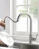 A person is washing a plate under a kitchen faucet with a pull-down sprayer. Produktbild-Vorschau