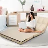 A woman is sitting on a beige floor sofa in a bedroom, using a laptop. Podgląd zdjęcia produktu