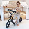A young boy is posing with a scooter in a bedroom. Produktbild-Vorschau