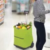 A person is pushing a green shopping trolley filled with groceries in a supermarket aisle. Produktbild-Vorschau