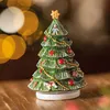 A ceramic Christmas tree figurine with ornaments and a star on top, placed on a wooden surface with bokeh lights in the background. Produktbild-Vorschau