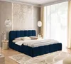A bedroom scene featuring a dark blue upholstered bed with a headboard and footboard, dressed with white bedding and pillows. The room has decorative wall art and sheer curtains.