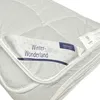 A close-up view of a white quilted blanket or duvet, folded to reveal a label. Produktbild-Vorschau