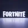 A lit-up Fortnite logo sign is displayed on a reflective surface against a dark background. Anteprima dell’immagine prodotto