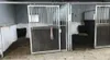 Two empty horse stalls with hay on the ground. Produktbild-Vorschau