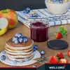 A breakfast scene with pancakes, fruit, jam, and a bowl of cereal. Produktbild-Vorschau