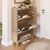 A wooden shoe cabinet with multiple shelves and flip-down drawers, filled with shoes, placed in a hallway next to a door. Podgląd zdjęcia produktu