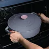 A person is placing a gray Dutch oven into an oven. Anteprima dell’immagine prodotto