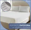A bed with white sheets and pillows, with a close-up inset of the fitted sheet's elastic edge. Produktbild-Vorschau