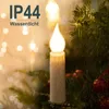 A close-up of a flameless LED candle light on a Christmas tree branch, with rain falling. Produktbild-Vorschau