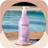 A bottle of Arkemusa Keratin Regenerating Conditioner is placed on a sandy surface with a pool in the background. Náhled obrázku produktu