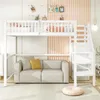 A white loft bed with stairs is shown above a gray sofa with yellow and gray pillows. The background features a light pink ribbed wall and white walls with photos clipped to strings.