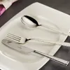 A set of silverware, including a knife, fork, and spoon, is arranged on a white plate. Produktbild-Vorschau