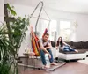 A couple relaxing in a living room with a hammock chair and a sofa. Anteprima dell’immagine prodotto