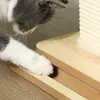 A cat's paw is shown reaching for a wooden scratching post. Produktbild-Vorschau