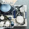 A top-down view of a dishwasher rack filled with pots, pans, and mugs. Produktbild-Vorschau