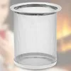 A close-up shot of a silver mesh tea strainer with a white base, set against a blurred background of a person and a fireplace. Produktbild-Vorschau