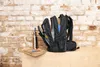 A black backpack is open and filled with items, placed on a wooden surface in front of a brick wall. Produktbild-Vorschau