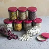 A collection of glass jars filled with various dry goods, arranged in a pyramid shape on a textured surface. Podgląd zdjęcia produktu
