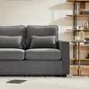 A close-up view of a dark gray sofa with decorative pillows, placed in a living room setting with a bookshelf in the background. Voir les images du produit