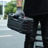 A person wearing gloves is holding a black tool case. Produktbild-Vorschau