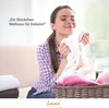 A woman is smelling a fluffy white towel, with a basket of pink and white towels in the foreground. Produktbild-Vorschau