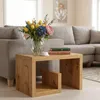 A wooden side table with a vase of flowers and books on it, placed in front of a sofa. Produktbild-Vorschau