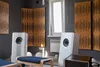 A room with acoustic panels on the walls, two white speakers, and a wooden bench with a blue cushion. Podgląd zdjęcia produktu