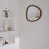 A mirror with a wooden frame is displayed on a white wall, next to a white shelf unit with decorative items. Anteprima dell’immagine prodotto