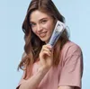 A woman is holding a tube of toothpaste in front of a light blue background. Anteprima dell’immagine prodotto