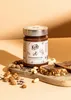A jar of nut spread with nuts and crackers on a wooden board. Produktbild-Vorschau