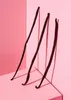 Three vanilla beans are arranged diagonally on a pink surface, with shadows cast on the pink background. Produktbild-Vorschau
