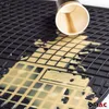 A close-up view of a black rubber car mat with a spilled cup of coffee on it. Produktbild-Vorschau