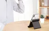 A person's arm is visible in the background, and a black phone stand with a white iPhone is on a wooden table. Náhľad obrázku produktu