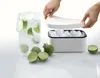 A hand is shown placing the lid on a white ice box filled with ice cubes. A pitcher of iced water with lime and mint is to the left, and limes are scattered around the ice box. Podgląd zdjęcia produktu