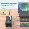 A multi-port USB charging station is shown connected to several devices, including a tablet and smartphones, on a wooden surface. Náhled obrázku produktu