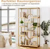 A gold metal bookshelf filled with decorative items and books, placed in a room with a large window overlooking an outdoor area. Podgląd zdjęcia produktu