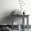 A table with decorative items and books against a wall. Náhľad obrázku produktu