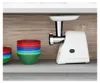 A white meat grinder is shown on a shelf next to a stack of colorful bowls. Anteprima dell’immagine prodotto