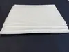 A stack of white disposable bed sheets on a dark surface. Produktbild-Vorschau