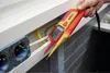 A hand holding a Wiha voltage and continuity tester near electrical outlets and wiring. Náhľad obrázku produktu