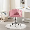 A pink velvet office chair with a shell-shaped backrest is placed on a white fluffy rug in front of a white vanity table. Produktbild-Vorschau