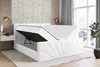 A white upholstered bed frame with the mattress and storage compartment lifted, revealing the storage space underneath. The bed is in a bedroom setting with a window and plant in the background. Produktbild-Vorschau