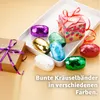 A collection of colorful curling ribbons and a gift box on a white tray, with a gift-wrapped box to the side. Produktbild-Vorschau