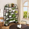 A plant stand filled with various plants and flowers is placed in a room with a window and curtains in the background. Produktbild-Vorschau