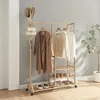 A wooden garment rack with clothes and shoes on it, placed in a room with a gray wall and wooden floor. Anteprima dell’immagine prodotto