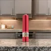 A red electric pepper grinder sits on a granite countertop in a kitchen. Náhled obrázku produktu
