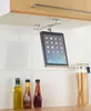 A tablet holder mounted under a kitchen cabinet, with bottles of oil and sauce on the counter below. Produktbild-Vorschau