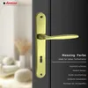 A close-up of a gold-colored door handle on a dark door, with a blurred background of a room interior. Produktbild-Vorschau