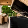 An outdoor patio setting with a table and chairs, and a storage box with its lid open. Produktbild-Vorschau